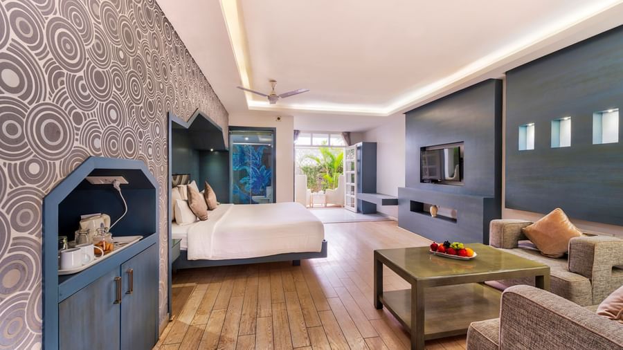 A spacious hotel suite featuring a bedroom area with a large bed and a separate living area with a sofa and coffee table | Grande Chalet | Grande Bay Resort & Spa, Mamallapuram
