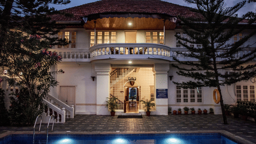 facade image of the abad dutch bungalow in fort kochi featuring a swimming pool in the front of the entrance