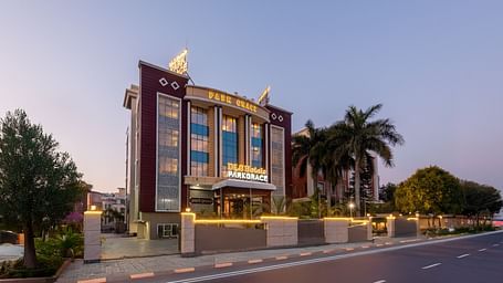 Exterior view of DLS Park Grace, Haridwar featuring well infrastructure, warm lighting, main road and the green surroundings.