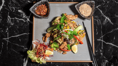 Gourmet Asian salad on a marble table at Asiatic Rooftop Bar and Restaurant, served with crisp greens, colourful vegetables, and two dipping sauces.