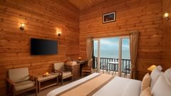 a hotel room with a double bed, a seating area, a wall-mounted television and a balcony with stunning vistas - Highland Sarovar Portico, Sindhudurg