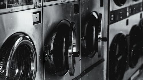 Row of modern washing machines in a laundry facility, reflecting a clean and convenient service setup.