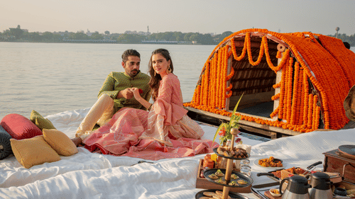 a newly wed couple sitting on a boat decorated with wedding ornaments - polo floatel kolkata