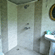 The Bird's Eye View Eco Cottage bathroom with stone walls, a bathtub, washbasin, and mirror at Wild Brook Retreat, Rajaji National Park.