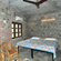 The Bird's Eye View Eco Cottage bedroom with rustic stone walls, wooden windows, and wicker chairs at Wild Brook Retreat, Rajaji National Park.