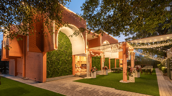 Decorative entrance archway with greenery and trees leading into the property at Mango Grove Hotel.