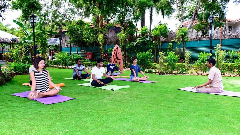 Guests doing Yoga on yoga mats kept on a lawn at our resort with activities in South Goa - Heritage Village, Goa