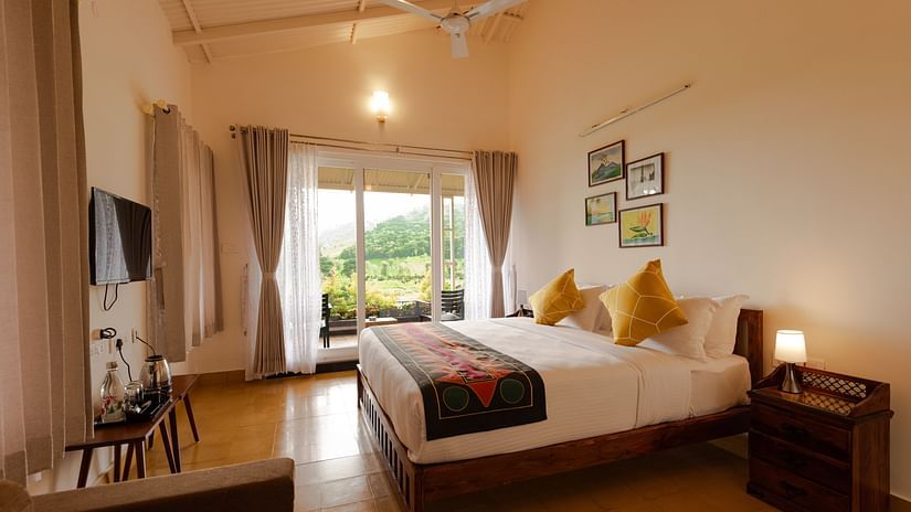 a double bed in front of a wall mounted tv in Bear Room - Ibex Stays & Trails, Kotagiri
