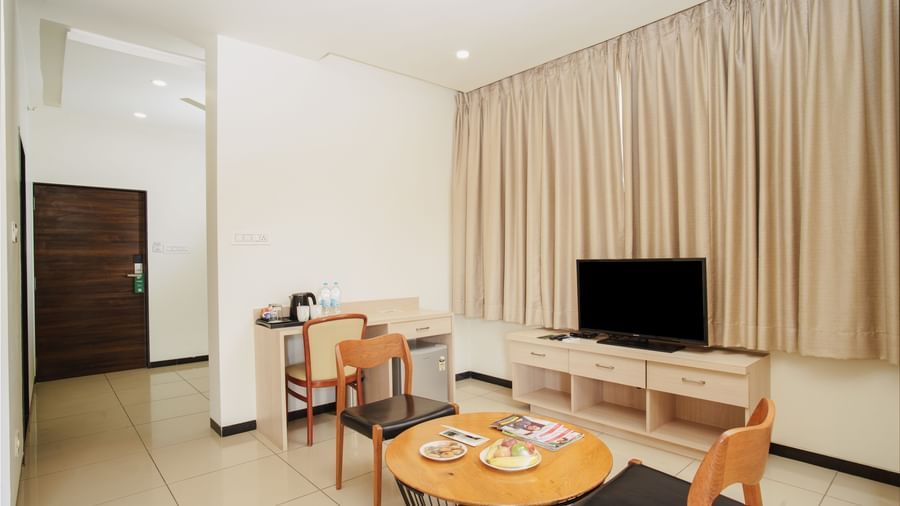 Hotel suite living room with a couch, small dining table, and a television cabinet at Arawali Ananta Elite, Jaipur.