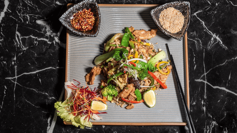 Gourmet Asian salad on a marble table at Asiatic Lounge, served with crisp greens, colourful vegetables, and two dipping sauces.