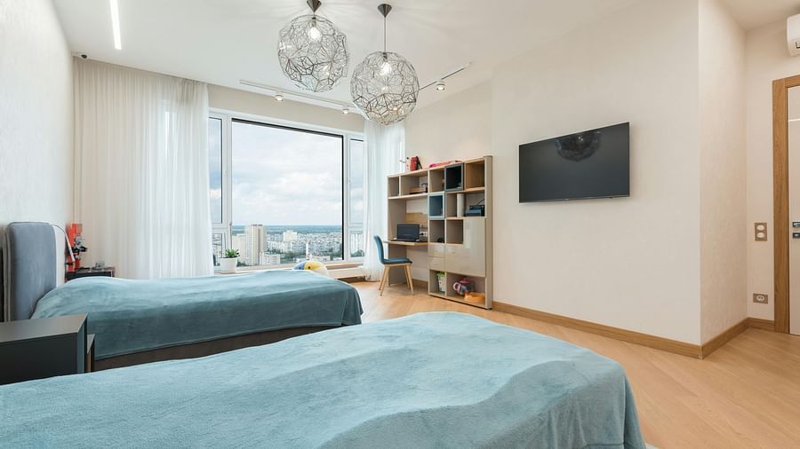 an image of a twin bedroom with a television and a light hanging from the ceiling