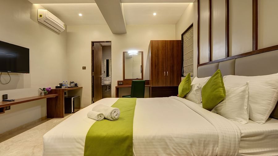 A double bed with a tv opposite it inside Classic AC Room - Fortune House, Magarpatta