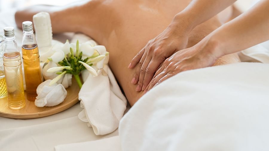 A lady getting a massage with various spa products kept on table