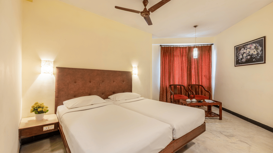 Double room at Jayaram Hotel, Pondicherry featuring comfortable bedding, cosy seating and contemporary interiors.