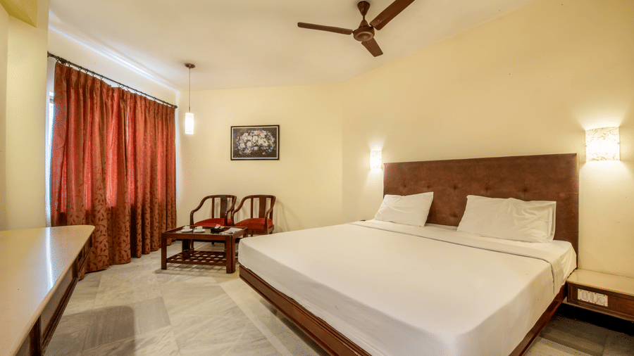 Deluxe bedroom at Jayaram Hotel, Pondicherry with a comfortable double bed, seating area and modern amenities.