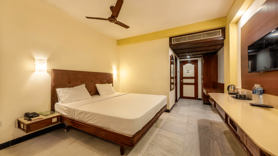 Comfortable Deluxe Room at Jayaram Hotel, Pondicherry featuring a double bed, television, work desk and elegant interiors.