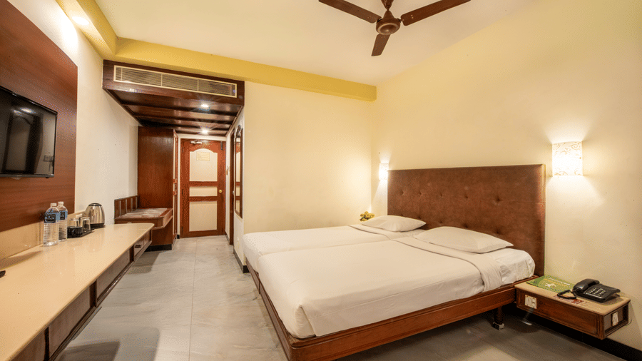 Standard Room at Jayaram Hotel, Pondicherry featuring a comfortable bed, television, work desk and contemporary interiors.