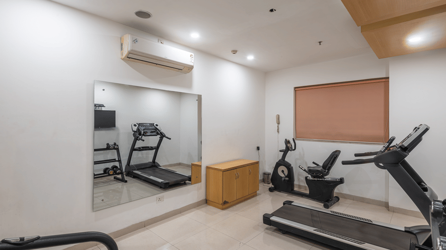 Well-equipped fitness room at Mango Grove featuring treadmills and exercise machines.