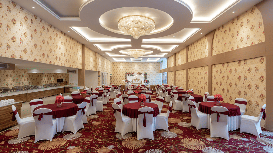Banquet hall set up with round tables in maroon and white linen at Mango Grove Hotel.