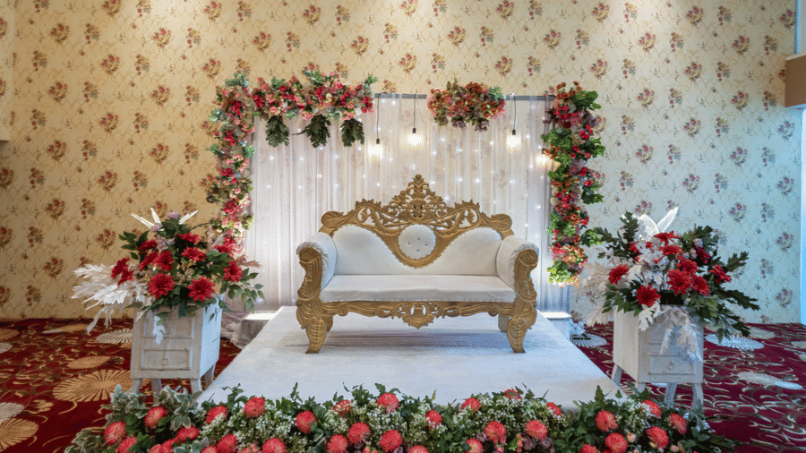 Wedding stage decorated with a floral arch and ornate seating at Mango Grove Hotel.