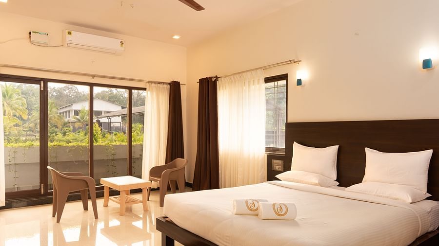 A double bed with chairs next to it inside deluxe ac room - Mastiff Select Terrain