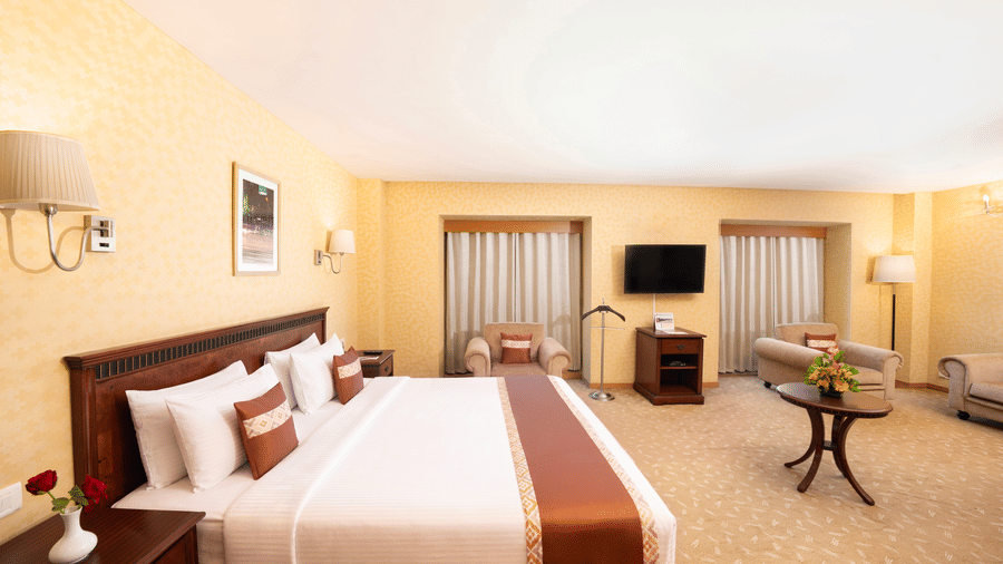 A room with a large bed, spreads, pillows, a table, a window, and a table. | MGM Mark Whitefield