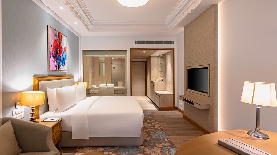 a double bed, side table with a lamp on it, a work desk with a lamp, and a television inside one of the rooms at Park Plaza, Jalandhar