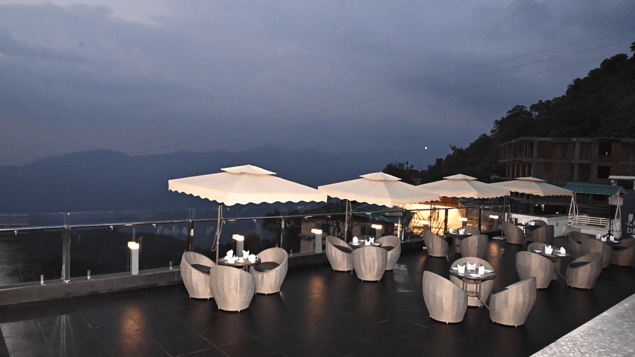 Sky Deck restaurant at Pride Ashiyana Resort Mussoorie featuring outdoor dining setup with a view of hills and valleys.
