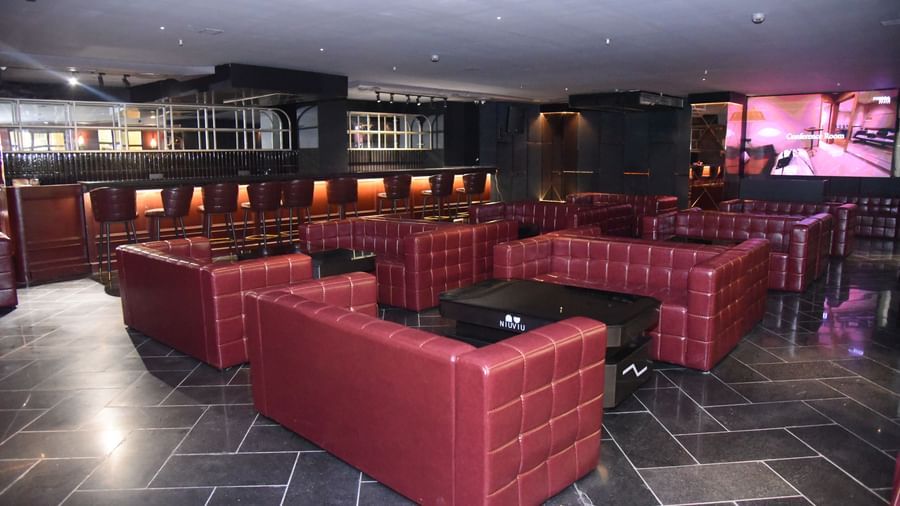 Stylish lounge with red leather sofas, dim lighting, and a bar counter at Pride Elite Raipur.