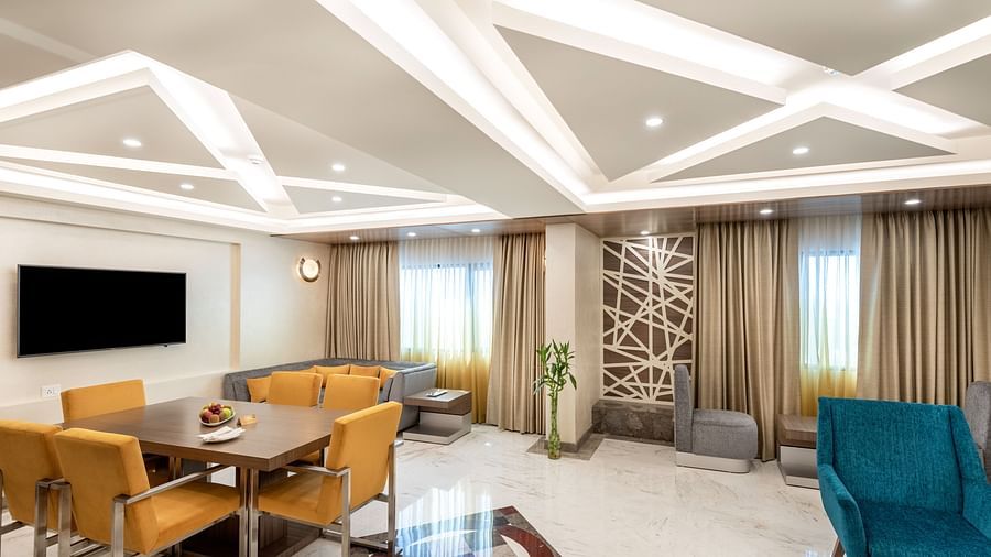 An image of a Luxury Suite with various seating arrangements in the form of sofa sets and dining table chair sets beside each other - The Suryaa New Delhi