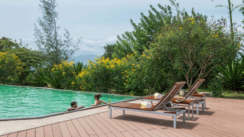 A couple enjoying a relaxing moment in the pool at its edge at The Serai, Bandipur.