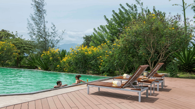 A couple enjoying a relaxing moment in the pool at its edge at The Serai, Bandipur.