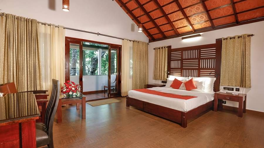 A bed in a villa that has other wooden furnishings and balcony | Vythiri Resort. Wayanad
