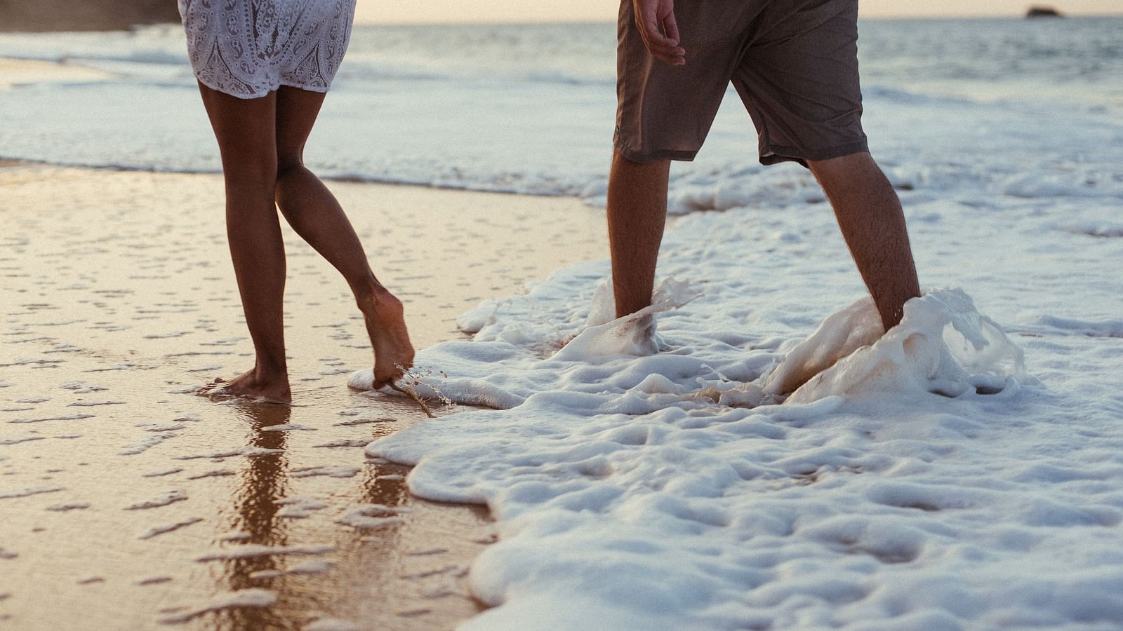 A couple walking barefoot along the beach, enjoying the gentle waves and the serene coastal atmosphere.