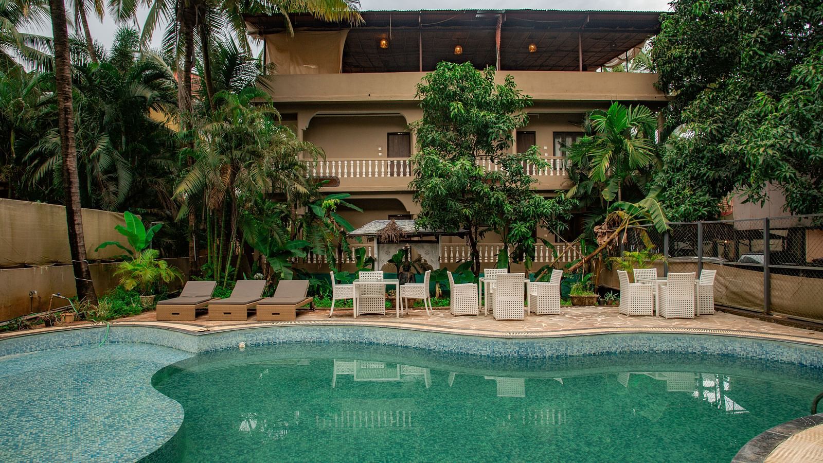 Outdoor swimming pool area with sun loungers and lush greenery at De Soul Santé, Morjim