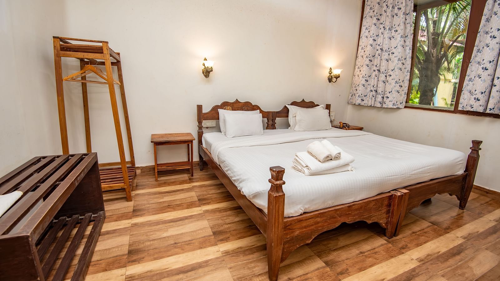 Neatly arranged bedroom with a bed, wooden accents, and a full-length mirror at De Soul Santé, Morjim.