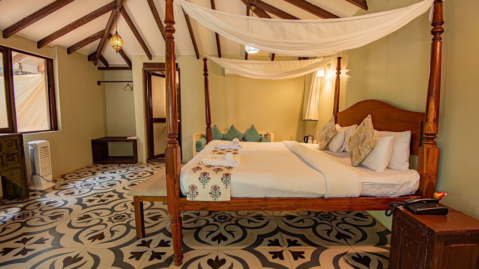 Elegant canopy bed in a spacious room with patterned flooring and warm lighting at De Soul Santé, Morjim.