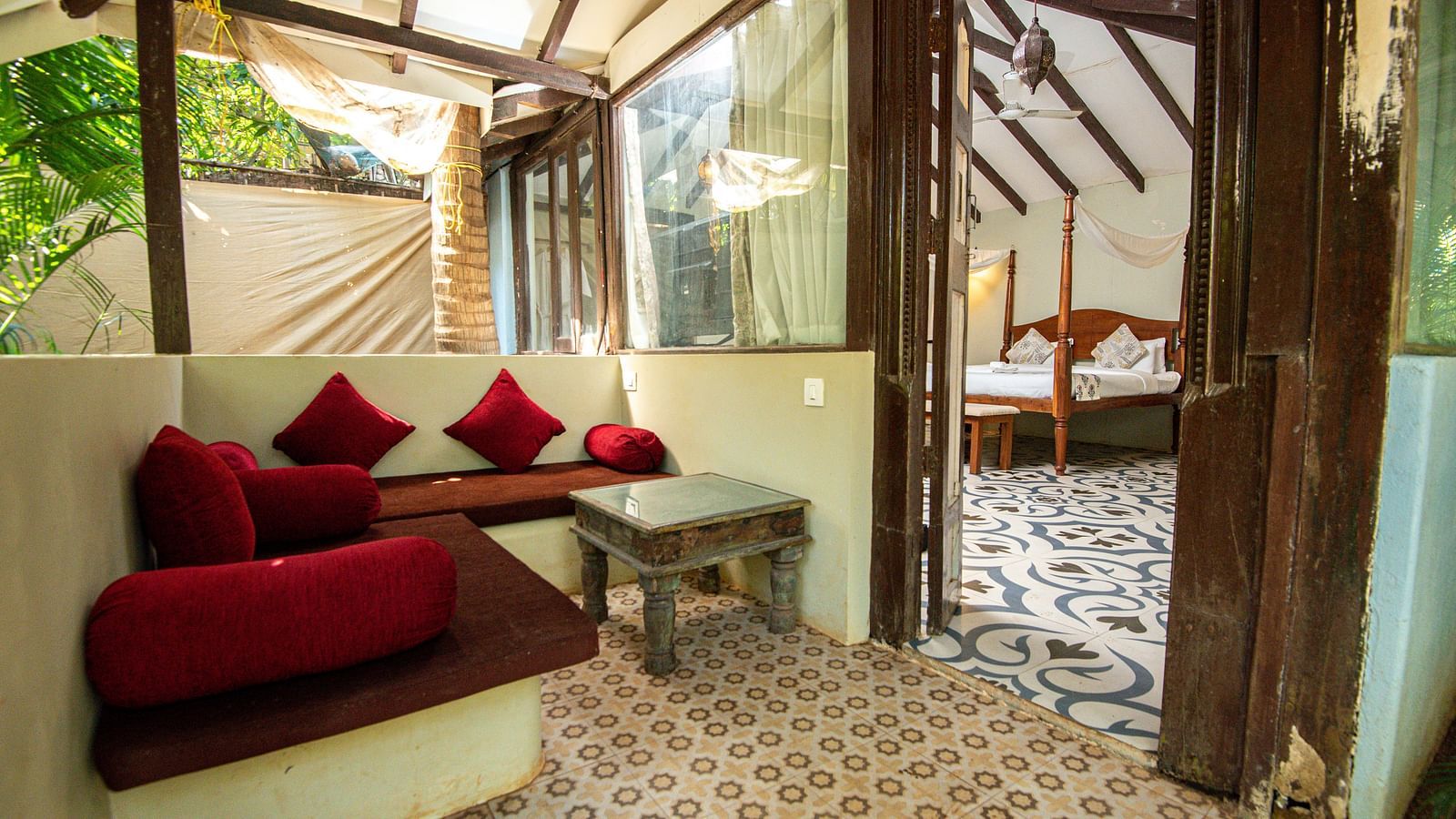 Cosy seating area in a rustic-style room with wooden elements and glass walls at De Soul Santé, Morjim.