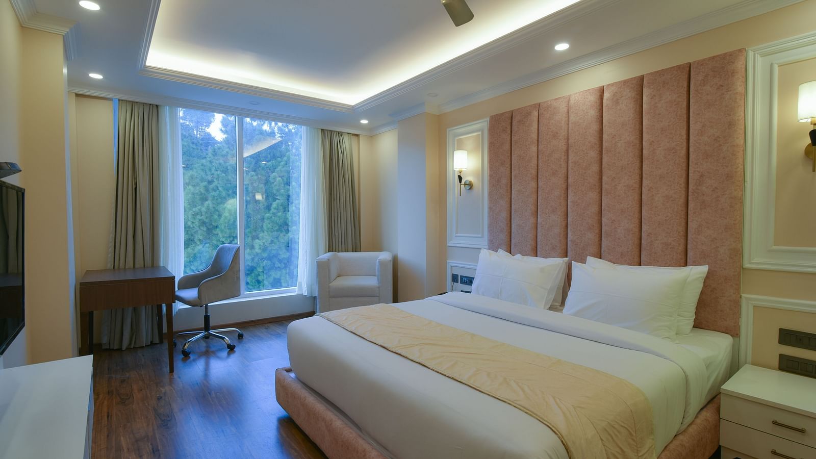A sleek hotel room with a king-sized bed, stylish lighting, and large windows providing scenic views of the natural surroundings. The decor is simple yet elegant.