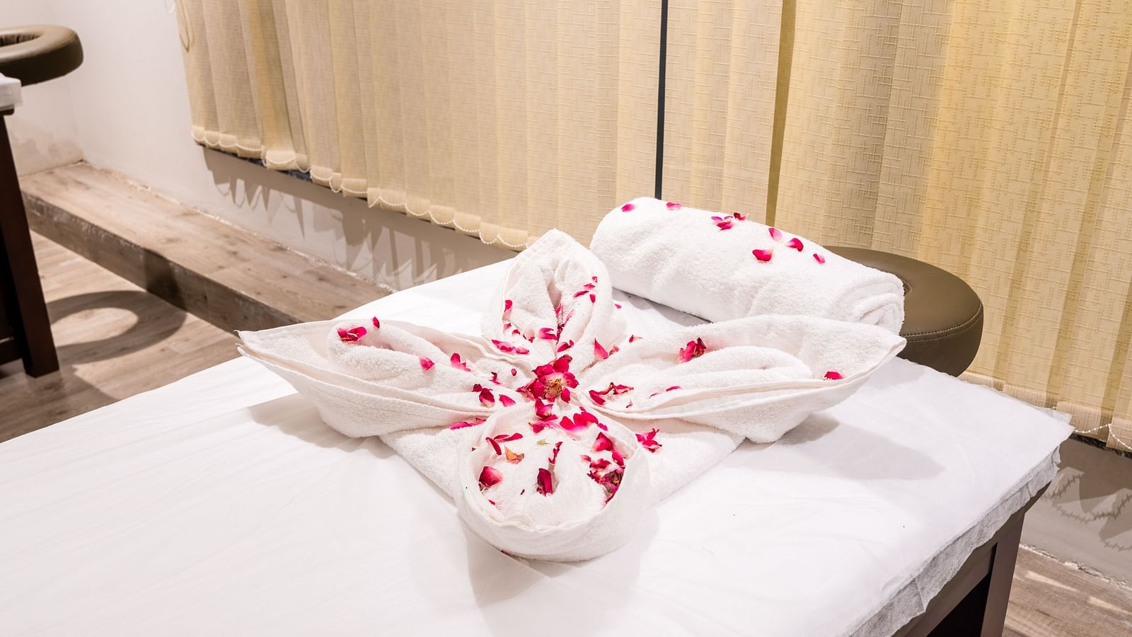 Closeup view of spa at DLS Divine Resort and Spa with towels and flower petals kept on the spa bed.