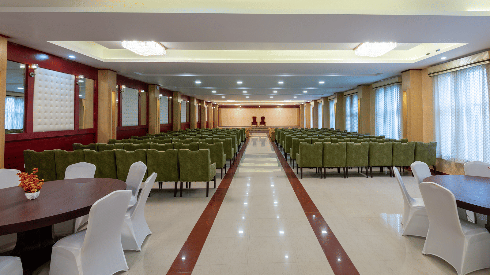A banquet hall at DLS Hotels featuring dining areas with round tables alongside theatre-style guest seating.