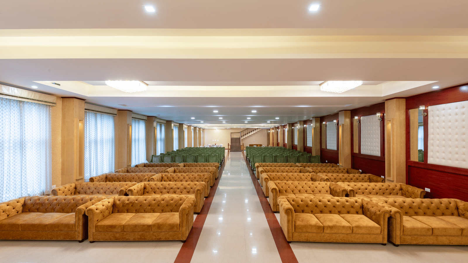 A DLS Hotels banquet hall featuring a long central aisle and organised rows of luxury seating on either side of the aisle.
