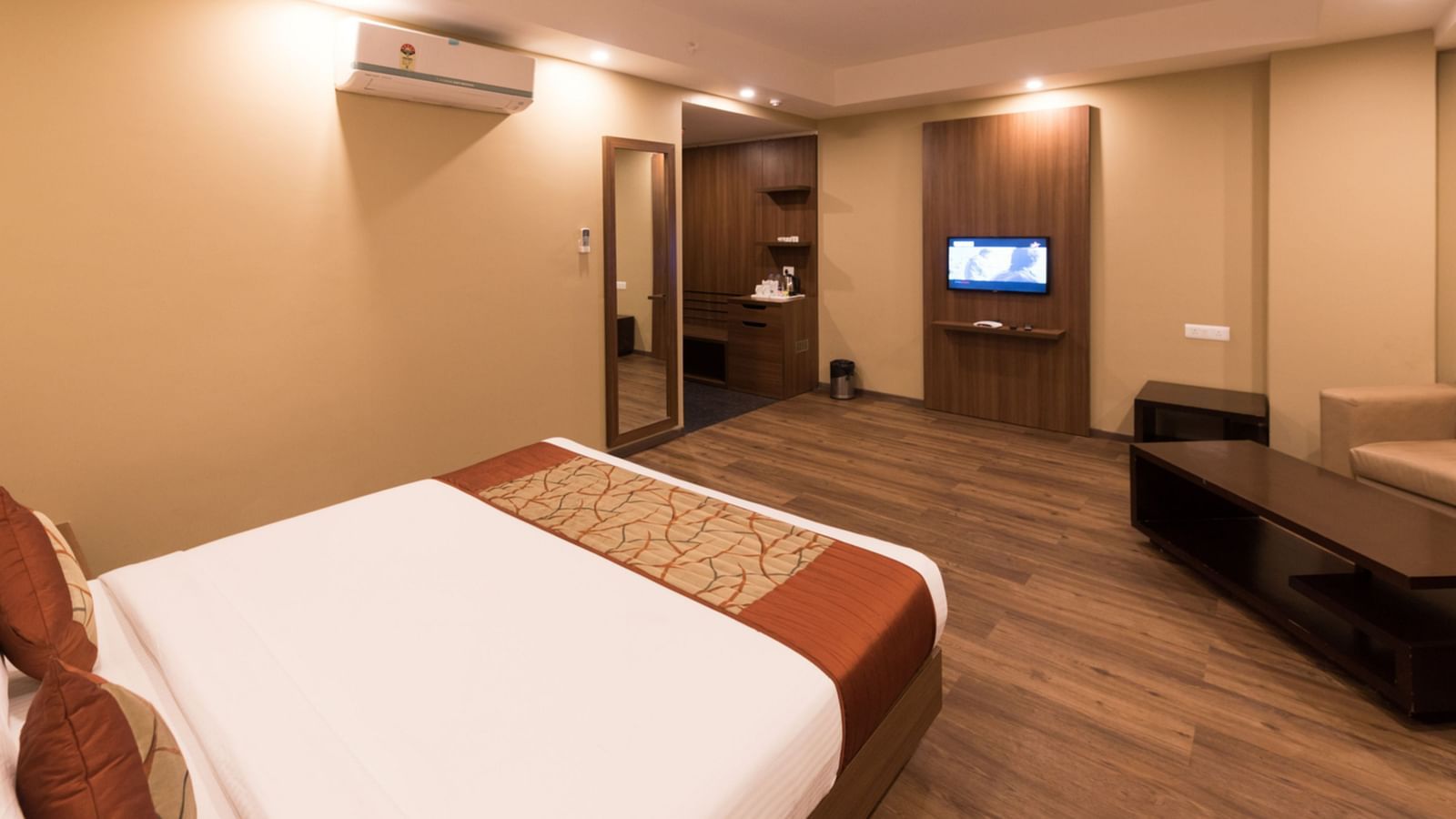 Super Deluxe Rooms with Complimentary Wi-Fi captured with a cosy bed and white linens along with a beige couch - Le ROI Digha Hotel West Bengal5