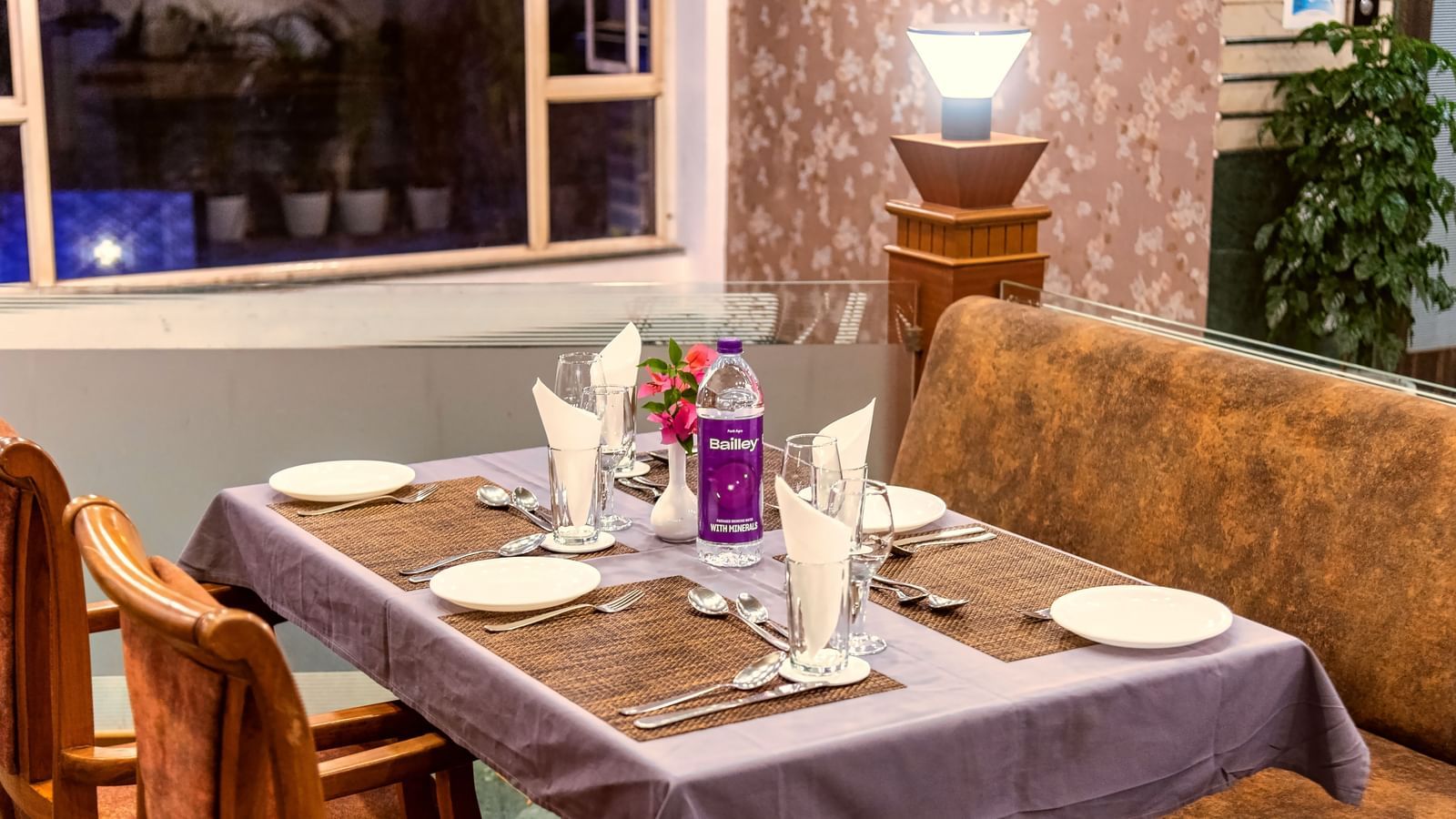 Cosy restaurant seating with a window view, elegantly set tables, and a warm ambience at Mayur Retreat.