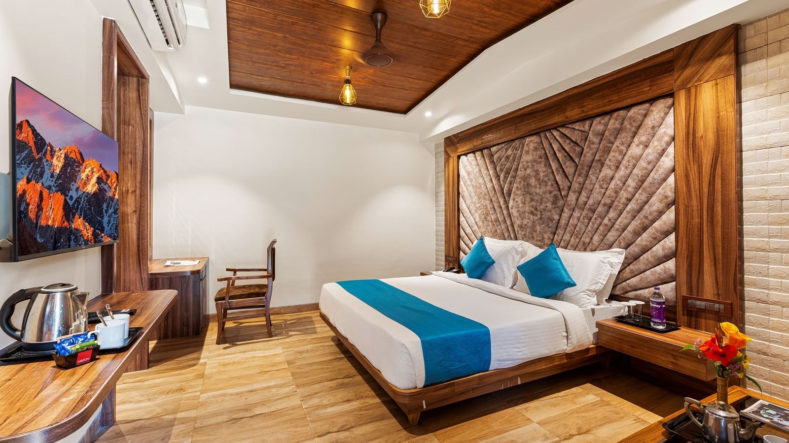 Elegant bedroom at Mayur Retreat with a blue-accented bed, wood interiors, ambient lighting, and a cosy sitting area.