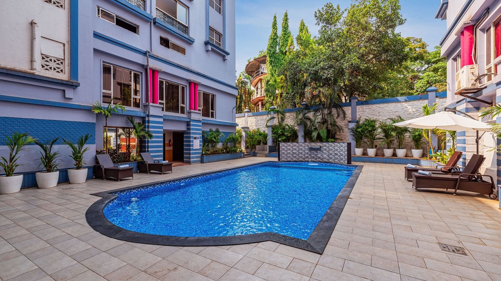 Outdoor swimming pool surrounded by the resort’s vibrant buildings, with poolside seating and lush greenery creating a refreshing leisure space.
