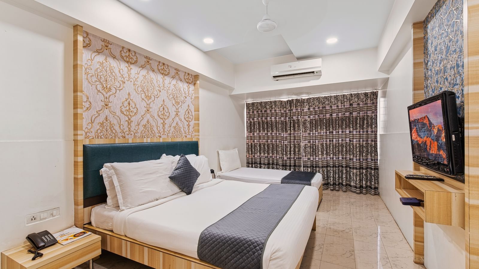 Modern hotel room with a king size bed and a singe bed at Mayur Retreat, contemporary lighting, and a flat-screen TV for a comfortable stay.
