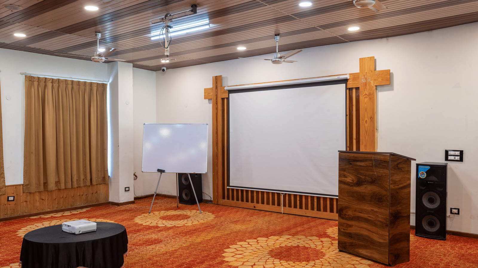 A projector screen with sound boxes beside it at DLS Hotels On The Ganges.