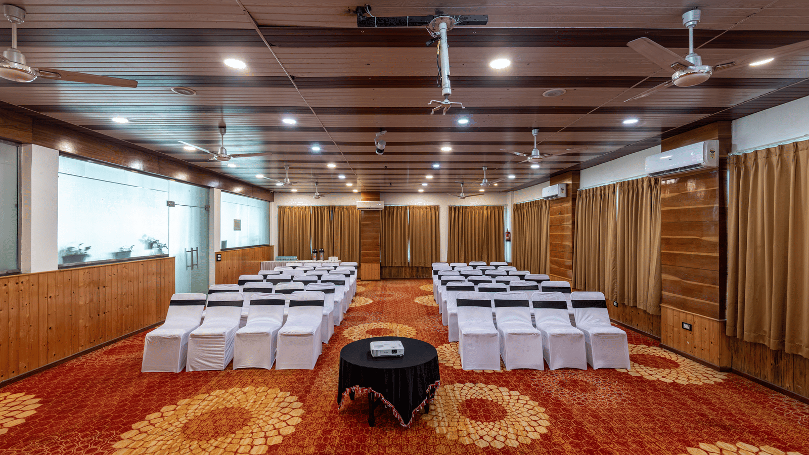 Banquet hall at DLS Hotels On The Ganges with chairs covered in white linen and orange decorative carpet.