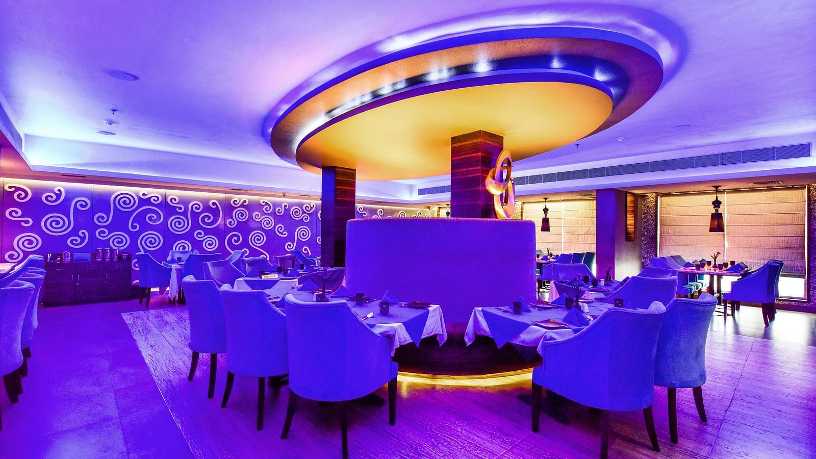 Image of Aqua Restaurant with sofa and a huge fancy light above it at  Swosti Grand, Bhubaneswar